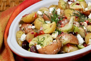 closeup of bowl of potato salad with dill, feta, celery, pimento, and Kalamata olives