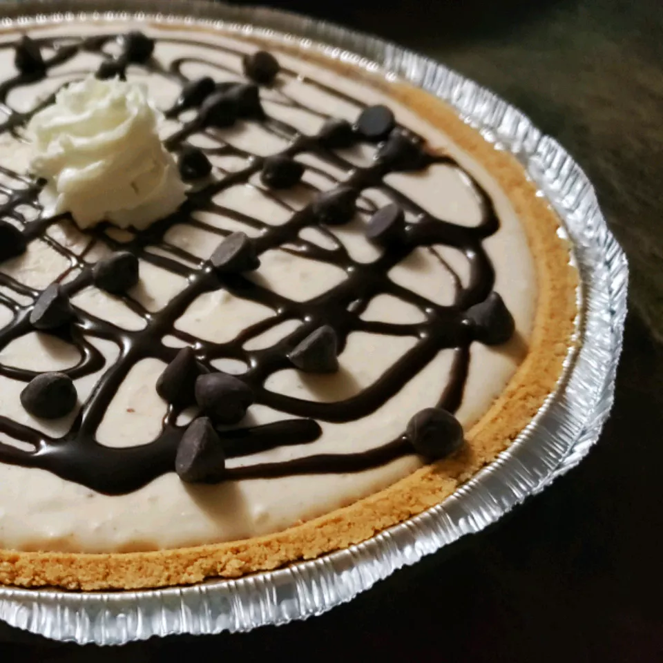 close up view of No Bake Peanut Butter Pie garnished with chocolate and cream in an aluminum foil pie plate