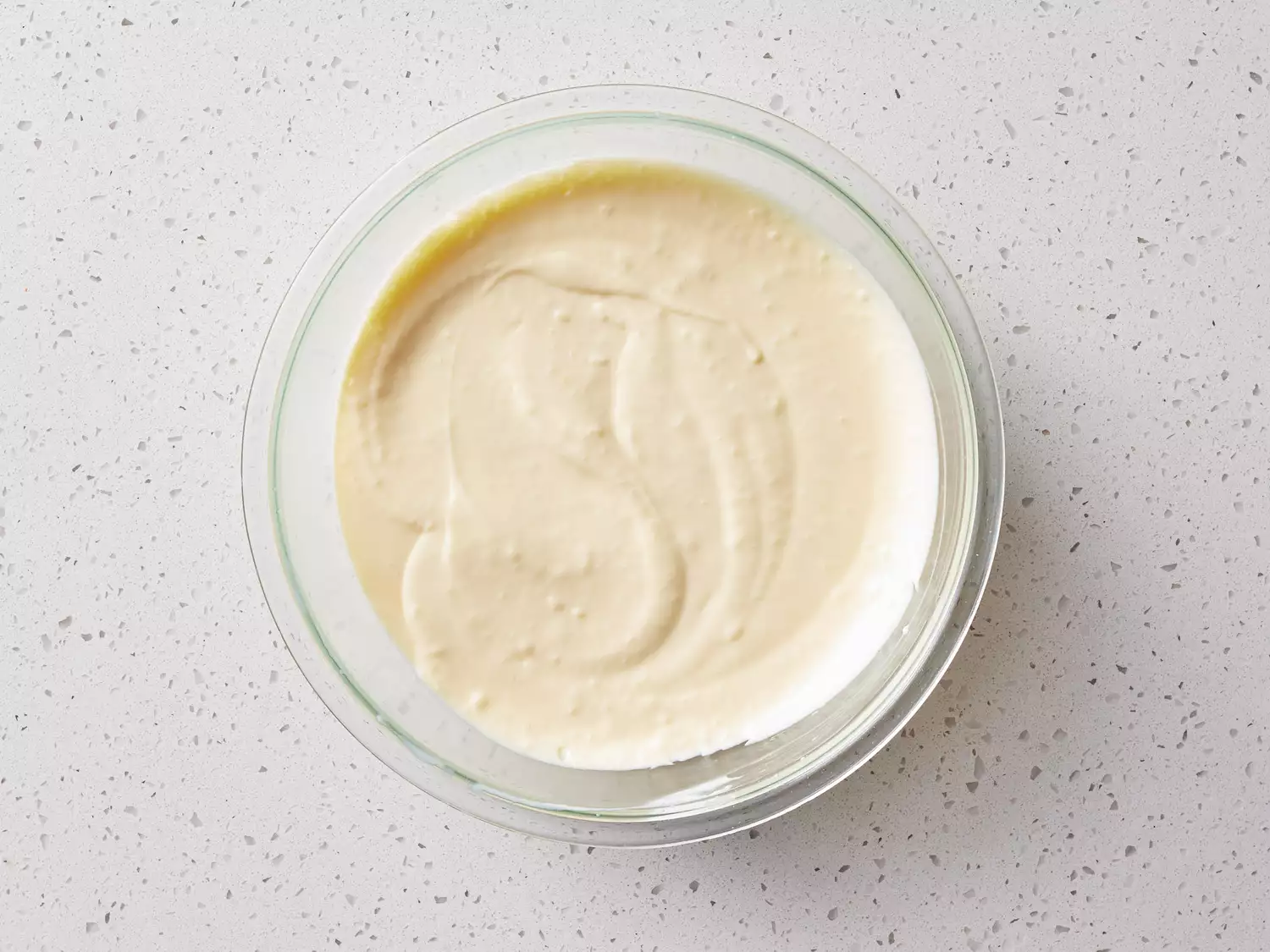 A glass bowl of whipped cream cheese, pudding mix, condensed milk, and milk