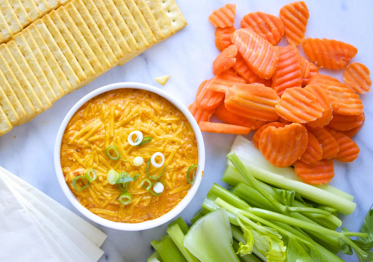 a bowl of Buffalo Chicken Dip on a platter with crudite and chips