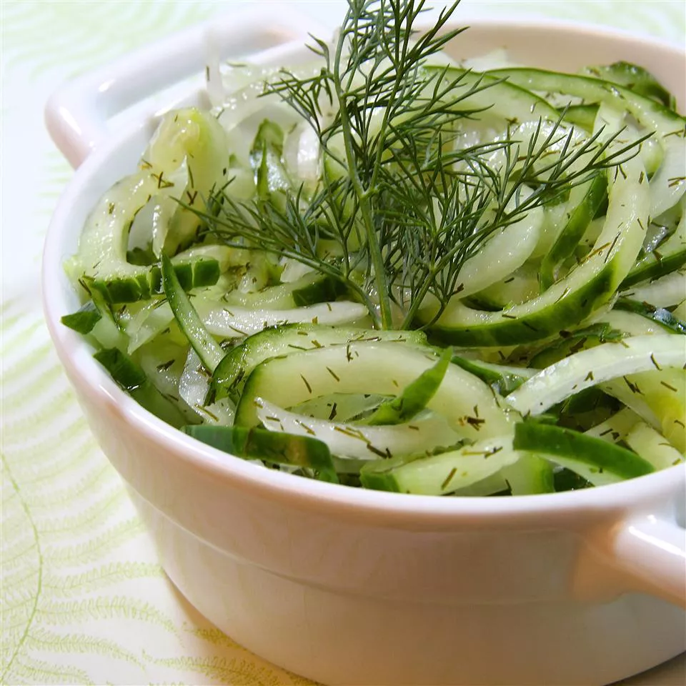 cucumber salad in white bowl with dill garnish